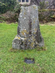 Photo of a standing stone on a green lawn with a house in the background. There is a small plaque in front of the stone which says: "Trouble. Aptly named. Gone but not forgotten." 