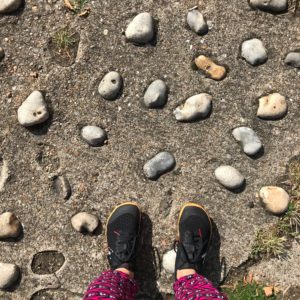 Photo of my feet in Vivo Barefoot Otillo shoes standing on stones.