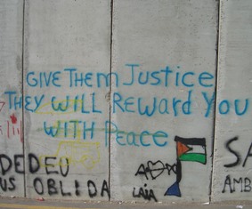 Inside of the Bethlehem wall with graffiti saying 'give them justice and they will reward you with peace.'