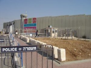 Outside of the Bethlehem wall with a distant poster saying: 'Peace be with you' by the Israeli tourism ministry.