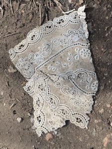 Photo of a paper doily on a bare soil path. The doily is shaped like the head of an Indian prince replete with turban.