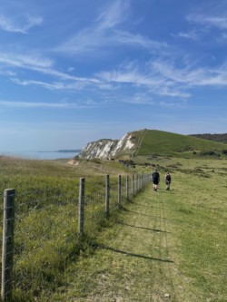 Photo of a coastal path. semi-white cliffs, and some walkers.