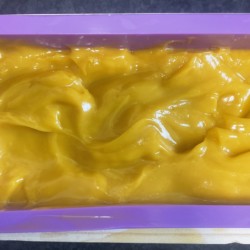Photo of some orange soap curing in a purple silicone and wooden box.